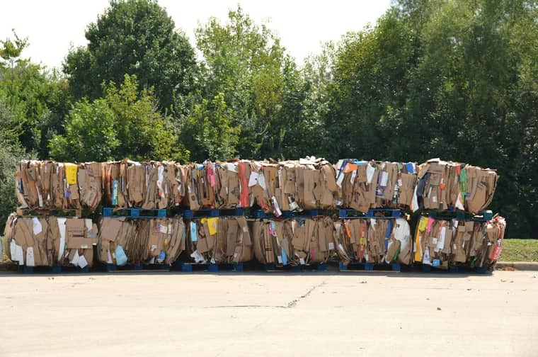 Neatly baled cardboard stacked on pallets in a recycling yard